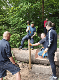 Contours use a sledgehammer to drive supporting posts into the ground beside the log steps.