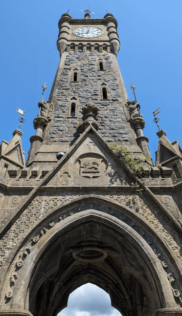 An upward view of Machynlleth's central clock tower, an ornately-carved free-standing structure situated at the far end of the high street.