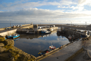 Boats nestled in the harbour at Seahouses. Photography by James West.